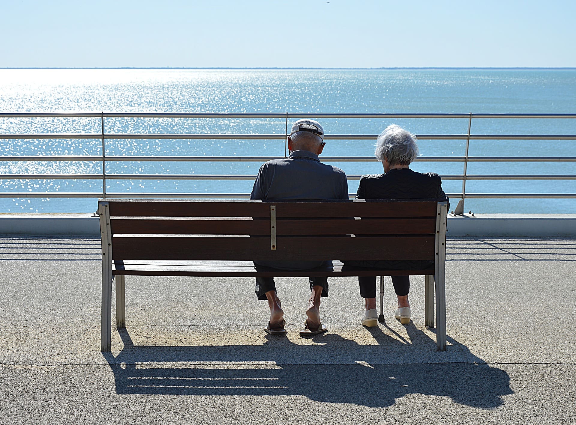 long-term care needs - two people sitting on a bench, looking out over the water