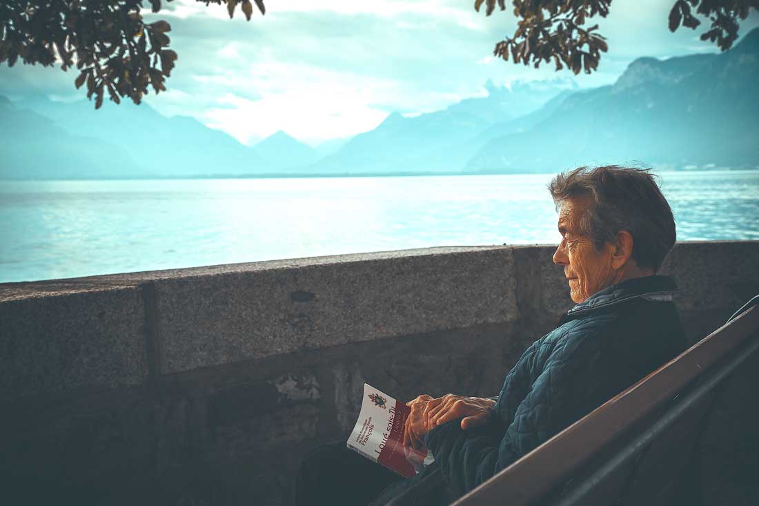 asset protection trust arizona - elderly person sitting on bench looking out across a lake near mountains