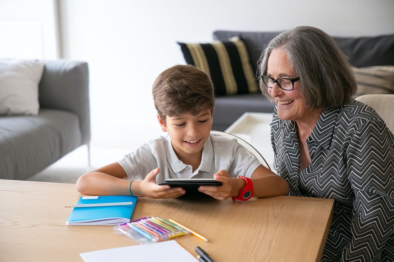 young boy showing grandma something on phone
