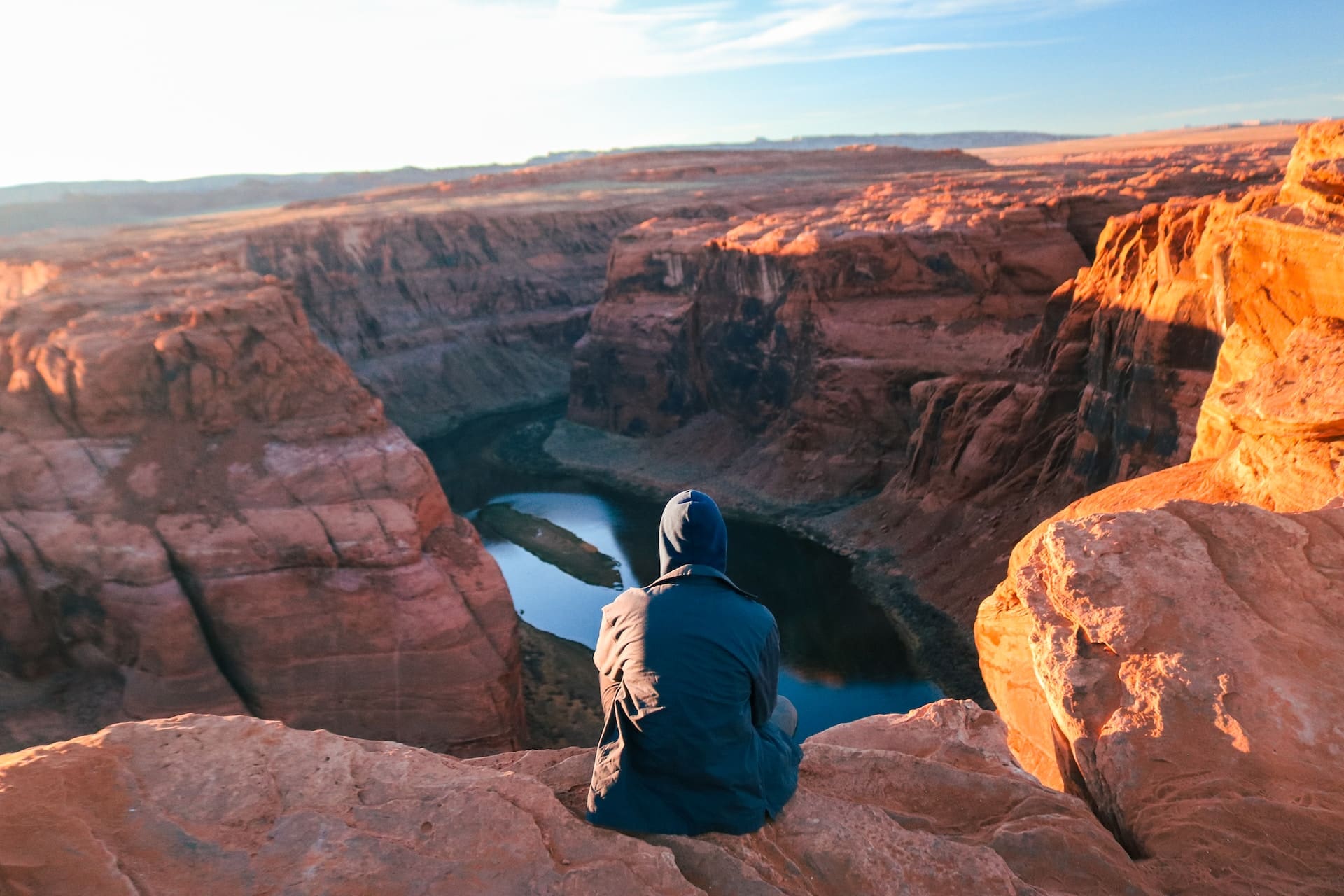 man in winter clothes sitting on edge of grand canyon