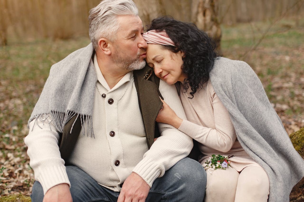 older man kissing wife on forehead