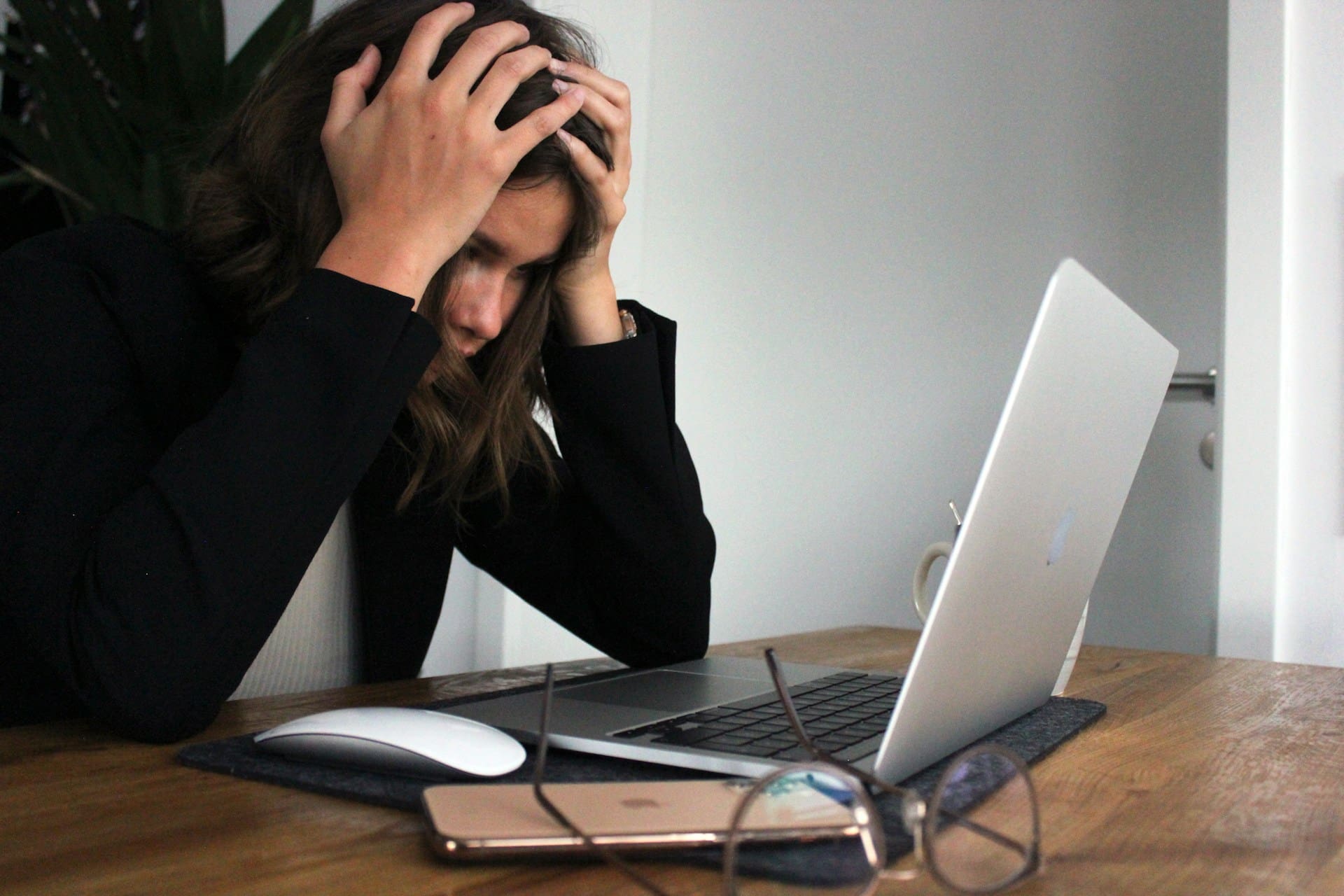 woman with head and hands staring at computer on desk