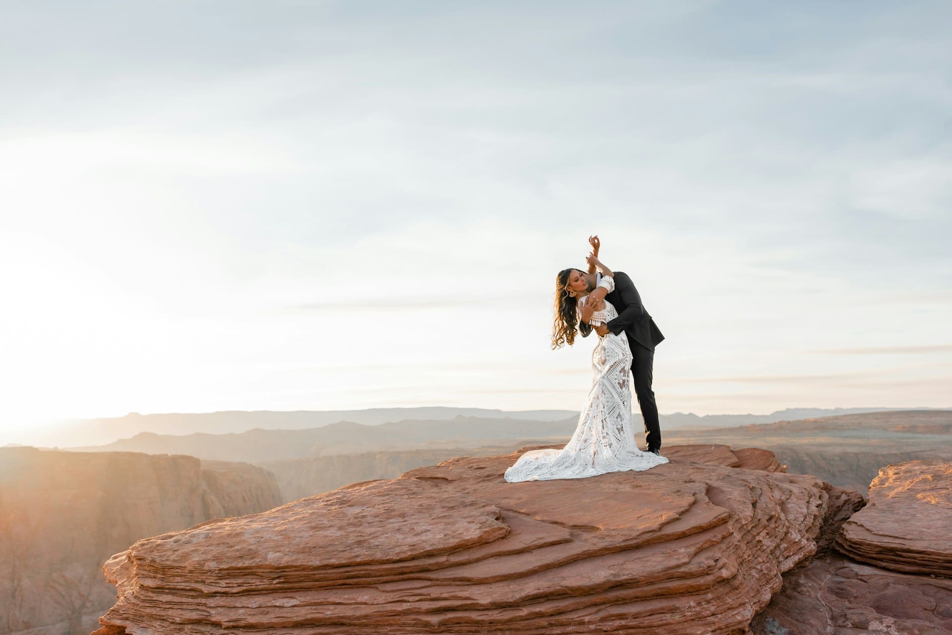 Wedding photo of couple standing on top/next to cliff