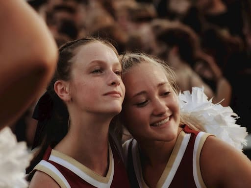 Two cheerleaders hugging and smiling