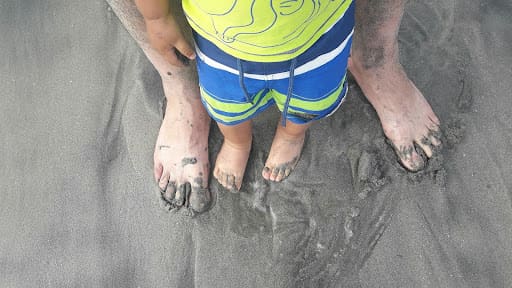 child and adult feet in sand