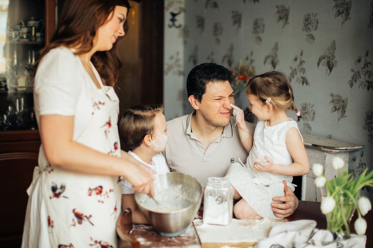 Husband, wife, and their two children making dough at their dinner table